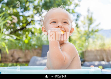 Junge sitzt im Baby Badewanne und das Essen von Früchten Stockfoto