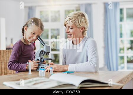 Mutter und Tochter zu Hause mittels Mikroskop Stockfoto