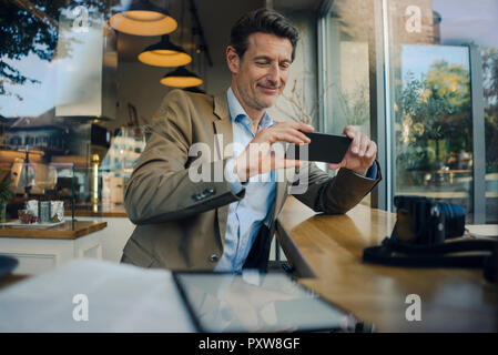 Reifen Geschäftsmann im Café sitzen, sie ihr Smartphone Stockfoto