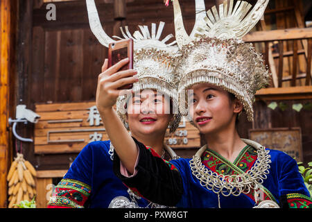 China, Yunnan, zwei Miao Frauen in traditionellen Gewändern und Kopfbedeckungen eine selfie mit Smartphone Stockfoto