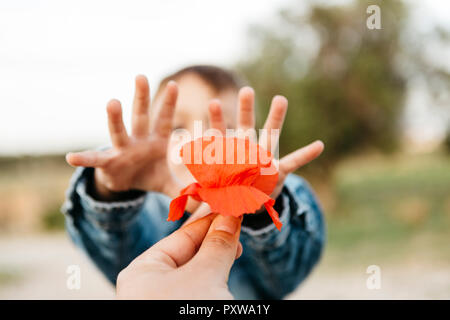 Der Vater von Hand mit einer Mohnblume an seinen Sohn Stockfoto