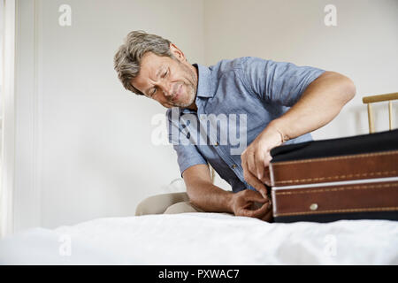 Reife Männer packen Koffer im Schlafzimmer Stockfoto