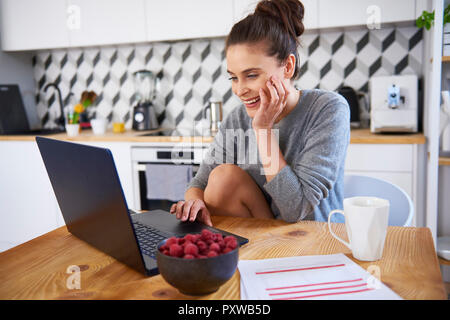 Junge Frau, die von zu Hause aus arbeiten, mit Laptop Stockfoto