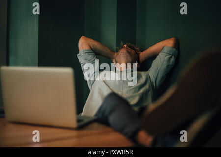 Müde Mann sitzt im Büro, zu spät in seinem Start-up-Unternehmen Stockfoto