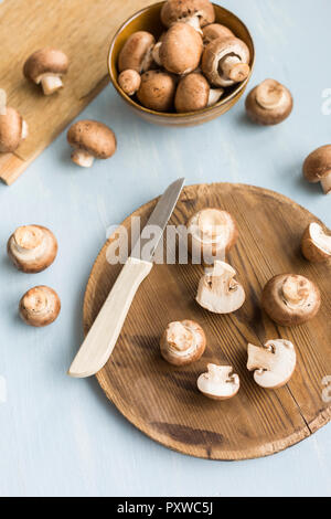 In Scheiben geschnitten und ganze Crimini Pilze auf Holzbrett Stockfoto