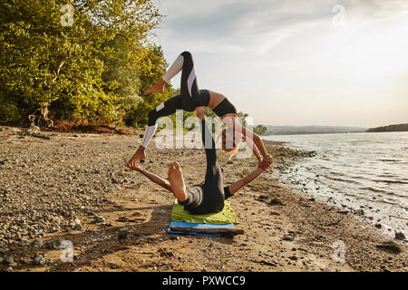 Junger Mann und Frau praktizieren Acro Yoga Stockfoto