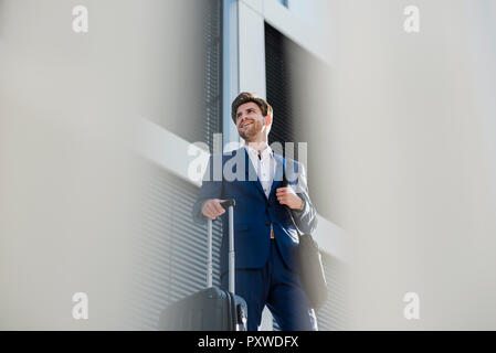 Lächelnd Geschäftsmann mit Gepäck in der Stadt umher, um die Stockfoto