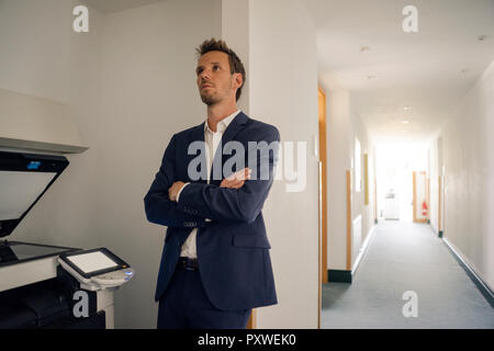 Gelangweilt Geschäftsmann lehnte sich gegen die Wand neben Kopiergerät Stockfoto