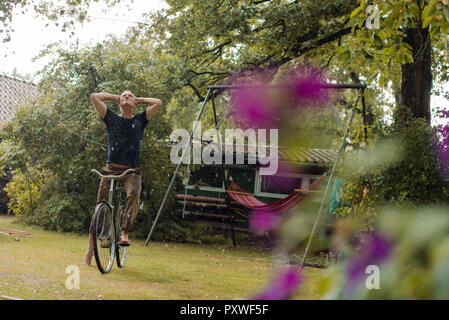 Reifer Mann mit Fahrrad genießen Sommer Regen im Garten Stockfoto