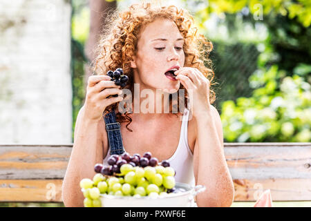 Porträt der rothaarige junge Frau Trauben essen Stockfoto