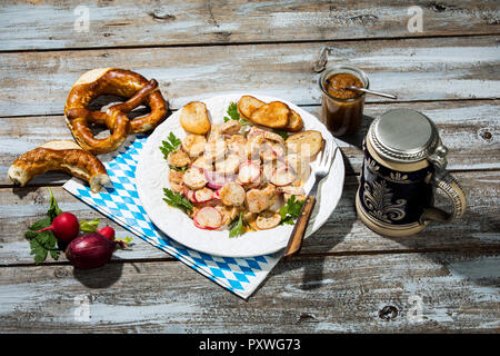 Weißwurst Salat mit gerösteten Brezel Brötchen, süßem Senf, Brezeln, rote Radieschen und Bierkrug Stockfoto