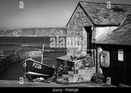 Schwarz-weiß Bild von Strand Fischerboot auf die Sennen Cove slipway neben alten Hafen Gebäude und Steintreppe. Stockfoto