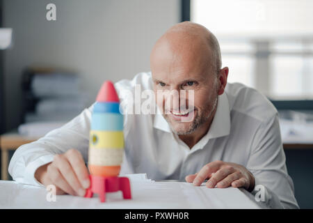 Geschäftsmann spielen mit Spielzeug, Rakete im Büro Stockfoto