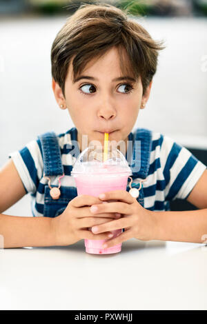 Portrait von kleinen Mädchen trinken Erdbeer milchshake an Cafe Stockfoto