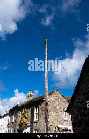 Starburst Form vieler Telefon oder Strom führenden Leitungen aus einem telegraphenmast führenden hoch in einem tiefblauen Himmel über Cottage Dächer Stockfoto