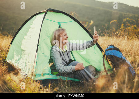 Ältere Frau ist Camping in Berg. Aktiven Ruhestand. Stockfoto