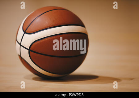 Basketball auf Holz- hof Etage Schließen mit unscharfen Arena im Hintergrund. Orange Kugel auf ein Hartholz Basketballplatz Stockfoto