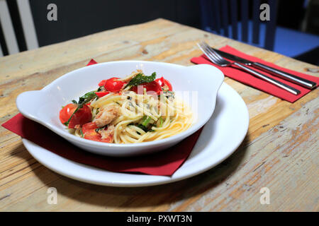 Linguine mit Krabbenfleisch mit Rucola, Tomaten und Chili, mit Olivenöl in einem Restaurant Einstellung fertig Stockfoto