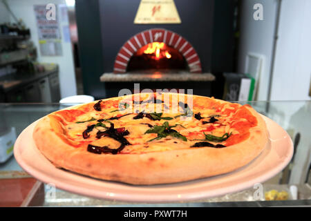 Schinken, Pilze, schwarze Oliven und Artischocken Pizza, in einem traditionellen Holzofen serviert Pizza Brennofen Stockfoto