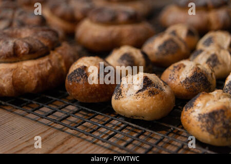 Frisch gebackene Brötchen und Brote sitzen auf einem Gitter abkühlen. Stockfoto