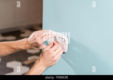 Elektriker, Arbeiter installiert Lichtschalter und Steckdose an der Wand im Zimmer. Schraubendreher, Nahaufnahme Elektriker Hände. Stockfoto