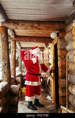 Der echte Weihnachtsmann klopft an die Tür der Hütte im Winter Forest. Stockfoto