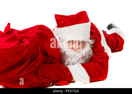 Santa Claus liegt mit einer Tasche von Geschenken. Auf weiß isoliert. Stockfoto