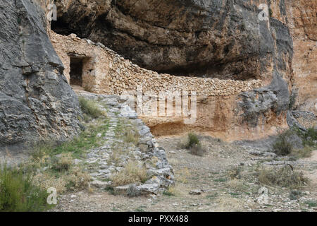 Eine Zuflucht für die Hirten und Tiere aus Stein Trockenbau in einer Höhle in der Red eisenhaltiges Gestein des Barranco de la Hoz Seca Canyon, Zaragoza, Spanien Stockfoto