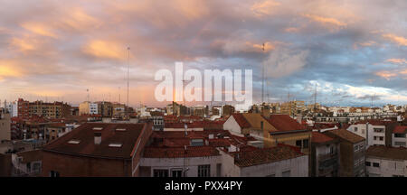 Ein Sonnenuntergang mit blauer Himmel, ein Regenbogen und orange und rosa Wolken nach einem Sturm, wie aus einem Wolkenkratzer über die Dächer mit Antennen in Zaragoza, Spanien Stockfoto