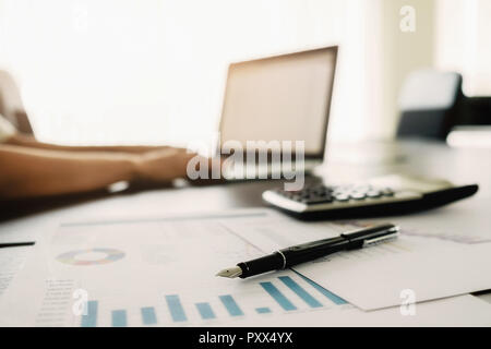 Geschäftskonzept mit Textfreiraum. Büro Schreibtisch Tisch mit Stift-Fokus und Analyse-Diagramm, Computer, Notebook, Tasse Kaffee am Schreibtisch. Retro Vintage Ton fi Stockfoto