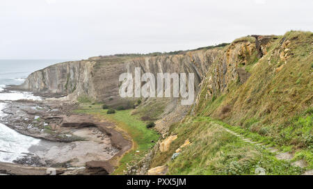 Eine Landschaft von einem Pfad auf der hohen Klippen auf rauer See während einer trüben regnerischen Tag vom Paseo de La Galea in Getxo Stadt, im Baskenland, Spanien Stockfoto