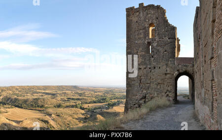 Der Turm mit einem Bogen über eine Straße der mittelalterlichen aufgegeben Montearagon schloss, neben gepflügten Feldern, im Sommer, in Aragon, Spanien Stockfoto