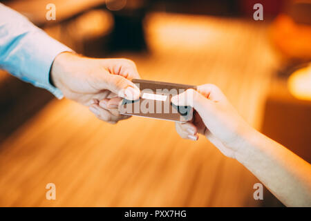 Männliche Hand geben Kredit- oder Debitkarte an weibliche Kassierer für die Zahlung im Shop oder Café Stockfoto