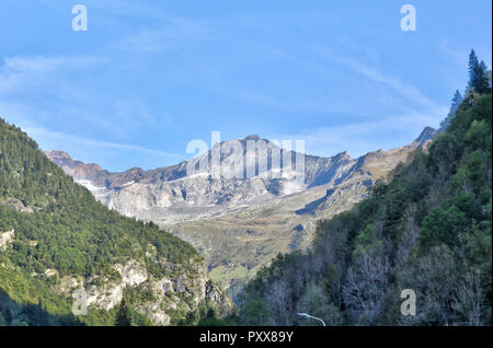 Eine Landschaft von blauen bewölkten Himmel, hohe Berge, Tanne und Kiefer Wälder und grüne Wiesen und Weiden im Val d'Otro, Region Piemont, Alpen, Italien Stockfoto