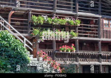 Eine typische Walser Lodge, aus Stein und mit hölzernen Balkonen mit Blumen Pflanzer und Treppenhaus, in Val d'Otro Tal, Alpen, Italien Stockfoto