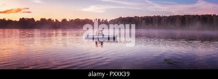 Paar in Love Ride in einem Boot auf dem See bei Sonnenuntergang. Romantischer Sonnenuntergang in der Goldenen Stunde. River Lake Nebel Liebespaar Ruderboot Datum beautifu Stockfoto