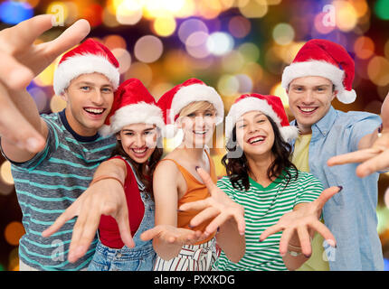 Gerne Freunde in santa Hüte über festliche Lichter Stockfoto