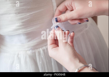 Ein Mädchen der Ehre hilft mit Binden Schleife Schärpe der Braut an ihrem Kleid. Stockfoto