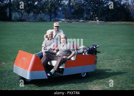 1970 s, zwei männliche Golfspieler in einer ungewöhnlichen Dreirädrige elektrischen Golfwagen, mit einem Deichselfuß-basierte Steuerung sitzen, USA. Es wurde in den 1950er Jahren, dass die Golf Katze oder Kart begann mehr beliebt bei Golfern zu werden, insbesondere den älteren Spielern. Die frühe elektrische Golf Autos waren auf Golfplätzen mit einer relativ flachen Gelände wie ihre Batterien benutzt hatte ein kurzes Leben. Stockfoto