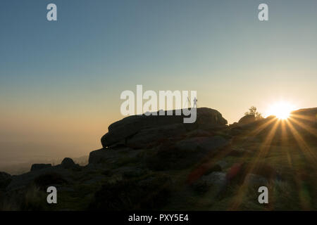 Silhouette eines Fotografen mit einem Stativ einrichten Landschaft Fotos der Sonnenaufgang auf Ilkley Moor von Kuh und Kalb Felsen, West Yorkshire, UK Stockfoto