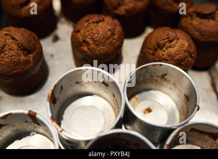 Frisch gebackene Muffins sitzen mit Dosen auf eine Bäckerei Zähler Stockfoto