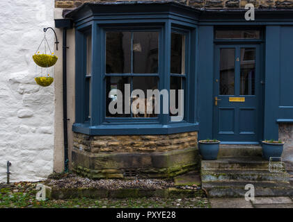 Hund in ein Erkerfenster eines alten Haus aus Stein, vereinbaren, Großbritannien Stockfoto