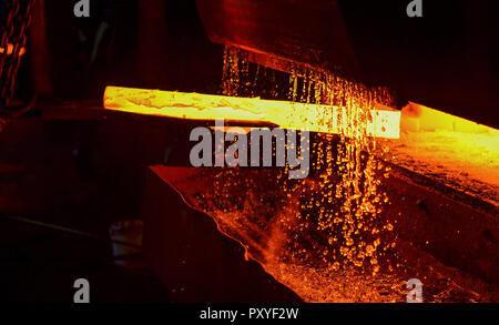 Heiße Eisen in den weiterverarbeitenden Betrieben, die ein Arbeitnehmer statt. Schmelzen von Metall in einem Stahlwerk. Hohe Temperatur im Schmelzofen. Metallurgische Industrie. Fabrik für Stockfoto