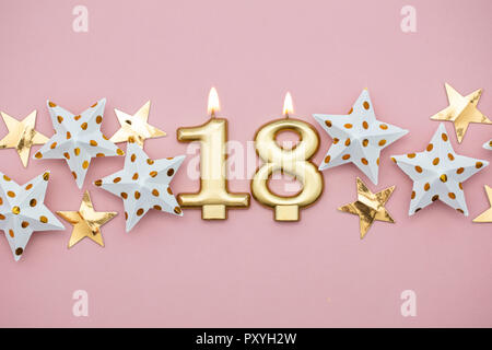 Die Zahl 18 Gold, Kerzen und Sterne auf einem Pastell rosa Hintergrund Stockfoto