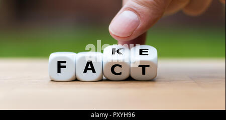 Hand dreht einen Würfel und Änderungen das Wort FAKE TATSACHE Stockfoto