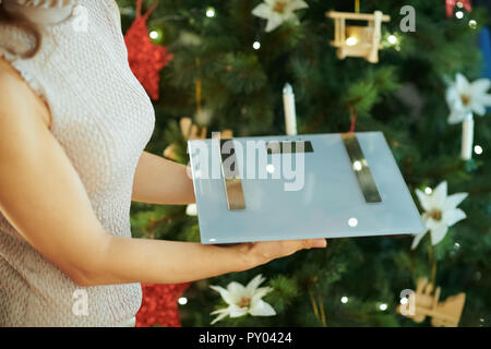 Junge Hausfrau in der Nähe von Weihnachten Baum holding Waagen Stockfoto