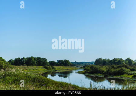 Ein kleiner Fluss in der Mitte des Feldes und grüne Vegetation, die durch die Flut des Flusses gebildet. Belarussische Polesien. Pripyat Nationalpark Stockfoto