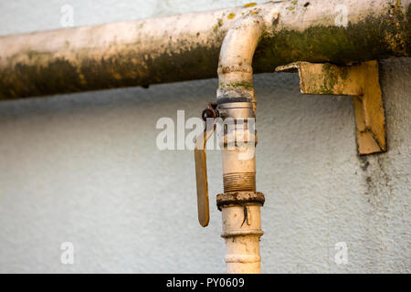 Close-up Detail des Alten schmutzig gelb lackiert Erdgasleitungen mit Schweißnähte und Hahn Ventil befestigt, um graue Hauswand. Sicherheit, Gefahr, alt und Stockfoto