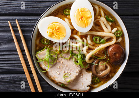 Würzige Udon Noodle Soup, Schweinefleisch, gekochte Eier, Shiitake und Zwiebeln close-up in einer Schüssel auf den Tisch. horizontal oben Ansicht von oben Stockfoto