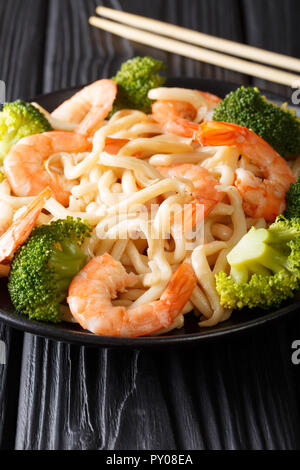 Japanische Küche: udon mit Garnelen und Brokkoli closeup auf einem Teller auf den Tisch. Vertikale Stockfoto